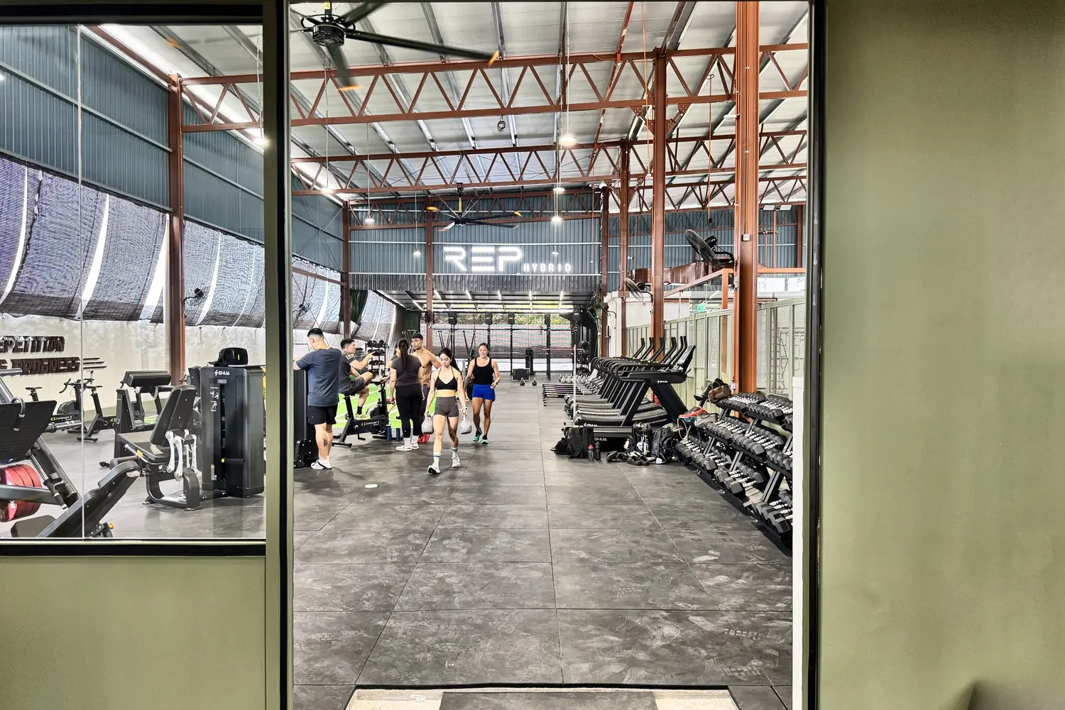 Looking through the doorway onto the main training floor, members walking under the REP HYBRID sign