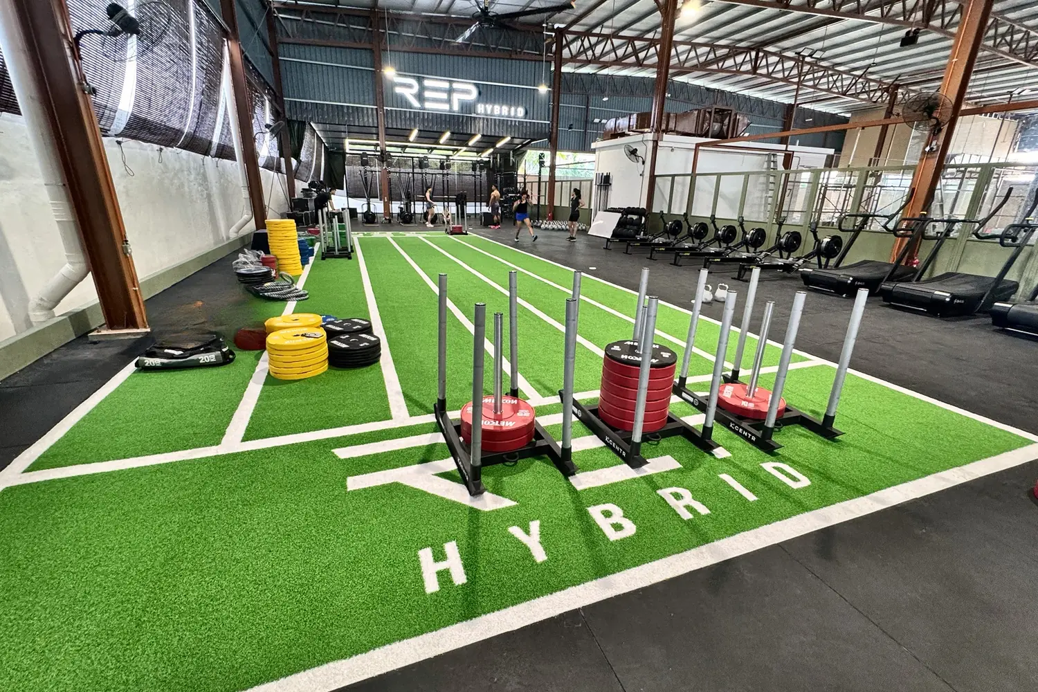 Loaded sleds on green turf lanes marked HYBRID, the REP sign at the far end
